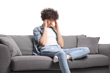 Genç adam beyaz arka planda izole edilmiş baş ağrısından muzdarip bir kanepede oturdu.