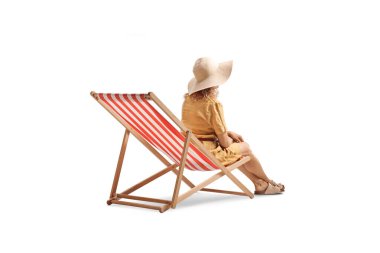 Güverte sandalyesinde oturan hasır şapkalı kadın beyaz arka planda izole edilmiş.