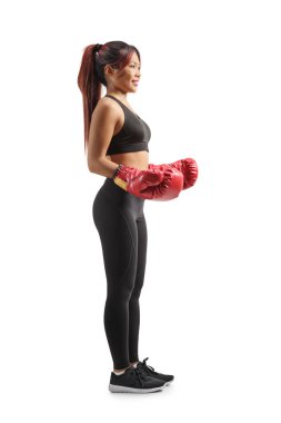 Beyaz arka planda kırmızı boks eldivenli genç bir Asyalı kadının tam boy profil çekimi.