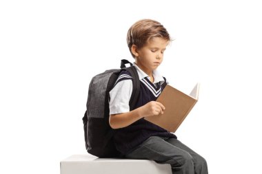 Öğrenci beyaz arka planda izole edilmiş bir kitap okuyup oturuyor.