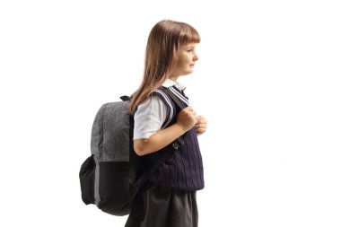 Okul üniformalı kız beyaz arka planda izole edilmiş bir sırt çantası taşıyor.