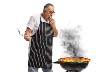 Beyaz arka planda izole edilmiş yanan bir bbq 'ın yanında duran adam