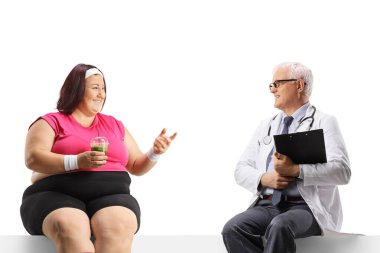 Şişman bir kadın erkek doktorla konuşuyor ve beyaz arka planda izole edilmiş boş bir panelde oturuyor.