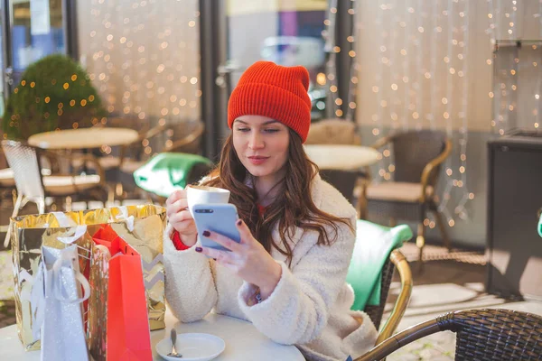 年轻美丽的黑发女子在咖啡店喝咖啡 并在网上购买圣诞礼物 — 图库照片
