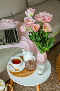 Evdeki rahat ofis. Evde çalış. Bahar dekoru. Örgü battaniye, bir buket lale, sıcak çay, dizüstü bilgisayar..