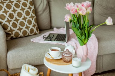 Evdeki rahat ofis. Evde çalış. Bahar dekoru. Örgü battaniye, bir buket lale, sıcak çay, dizüstü bilgisayar..