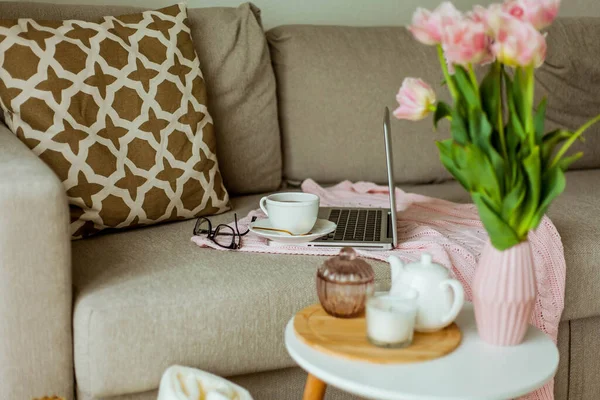 Home cozy office. Work at home. Spring decor. Knitted blanket, bouquet of tulips, hot tea, laptop.