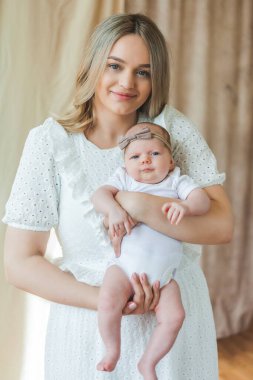 Mavi gözlü genç ve güzel bir anne yeni doğmuş kızını kollarında tutuyor. Annelik. Dikkat et. - Bebeğim. Ev.