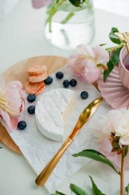 Beautiful breakfast. Fruits, berries, brie cheese, hot tea in mug, bouquet of pink peonies. Spring mood at home.