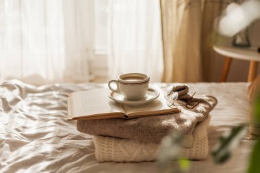 Hot mug of cappuccino on wooden tray on the bed, breakfast. Cozy house. Beige natural colors.