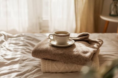 Hot mug of cappuccino on wooden tray on the bed, breakfast. Cozy house. Beige natural colors.