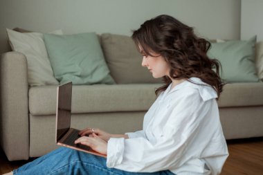 Güzel bir genç kadın evde dizüstü bilgisayarla çalışıyor. İçişleri Bakanlığı. İnternette çalış. Sosyal medya. Video görüşmesi.