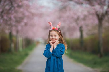 Paskalya. Uzun kıvırcık saçlı, kiraz çiçeklerinde tavşan kulaklı tatlı kız. Bahar.