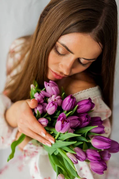 长发的年轻女子的画像 模型与一束紫丁香郁金香白色 — 图库照片