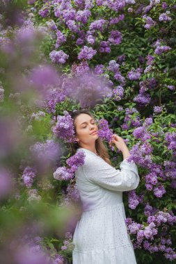 Çiçek açan leylağın yanında güzel mavi gözlü sarışın bir kadının portresi..