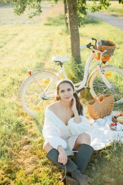 Sahada piknik yapan güzel siyah saçlı kadın. Bisikletli şık kıyafetler içinde bir model..