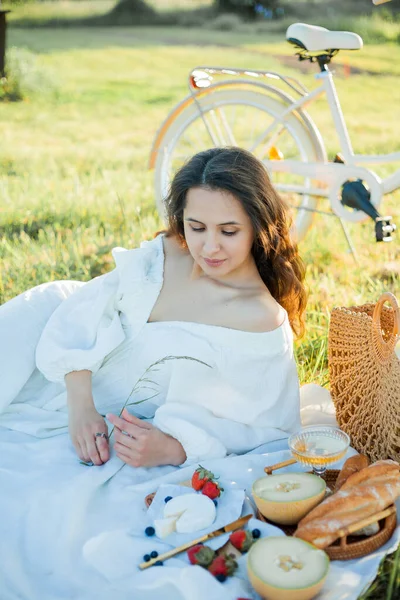 Stock image Beautiful young dark-haired woman on picnic in field. Model in stylish clothes with bicycle.