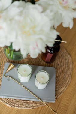 Evin içi rahattır. Mumlar, bir buket şakayık, ahşap sehpanın üzerinde cam vazoda..