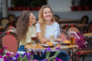 İki güzel kıvırcık kadın yazlık kafede oturup kahve içiyorlar. Sıcak ve soğuk içecekler. Rahibeler toplantıya sevindiler. Sıcak..
