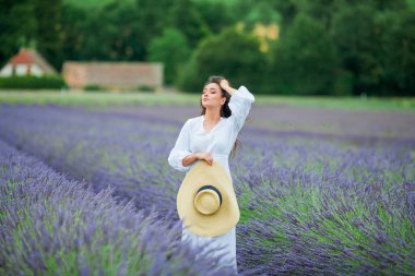 Lavanta tarlası. Güzel, siyah saçlı, kıvırcık saçlı, beyaz elbiseli, mor çiçekli bir kadın..