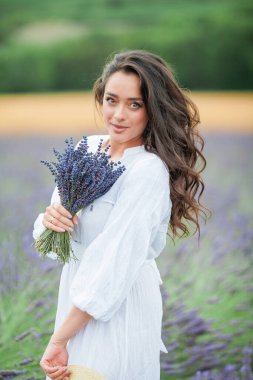 Lavanta tarlası. Güzel, siyah saçlı, kıvırcık saçlı, beyaz elbiseli, mor çiçekli bir kadın..