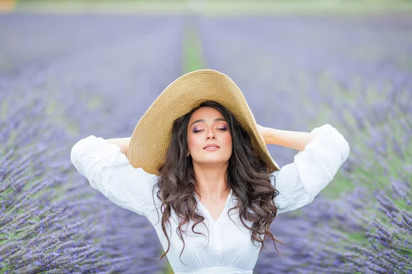 stock image Lavender field. Beautiful dark-haired curly woman in white simple dress in field of purple flowers.