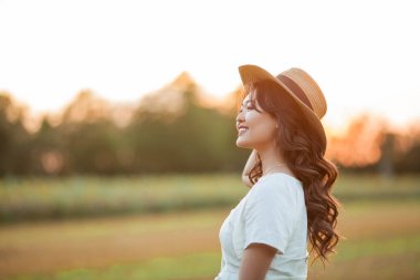 Gün batımında genç ve güzel bir Asyalı kadın sahada. Uzun kıvırcık saçlı bir model. Yaz, güneş.