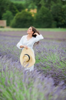 Lavanta tarlası. Güzel, siyah saçlı, kıvırcık saçlı, beyaz elbiseli, mor çiçekli bir kadın..