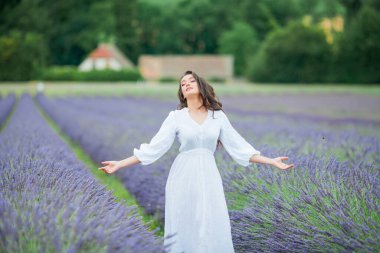 Lavanta tarlası. Güzel, siyah saçlı, kıvırcık saçlı, beyaz elbiseli, mor çiçekli bir kadın..