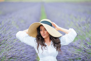 Lavanta tarlası. Güzel, siyah saçlı, kıvırcık saçlı, beyaz elbiseli, mor çiçekli bir kadın..