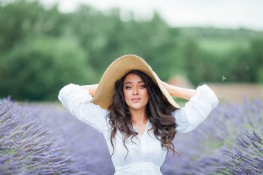 Lavanta tarlası. Güzel, siyah saçlı, kıvırcık saçlı, beyaz elbiseli, mor çiçekli bir kadın..