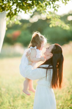 Beautiful young mother with little daughter on a picnic in the field. Summer breakfast with lemons.