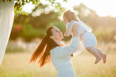 Beautiful young mother with little daughter on a picnic in the field. Summer breakfast with lemons.