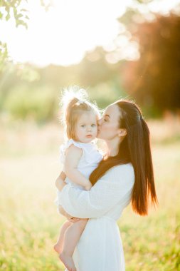 Beautiful young mother with little daughter on a picnic in the field. Summer breakfast with lemons.