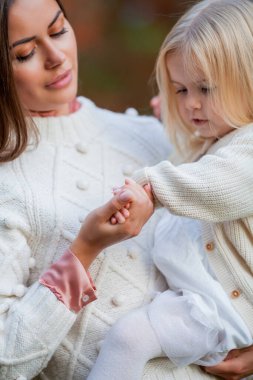 Güzel, genç, siyah saçlı anne, küçük kızıyla sonbahar parkında oynuyor. - Aile. Sonbahar.