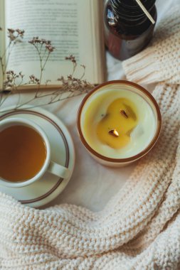 Ev dekoru. Kitap, örgü battaniye, mum, bir fincan sıcak çay. Sıcak bir sonbahar. Düş.