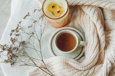 Ev dekoru. Örgü battaniye, mum, bir fincan sıcak çay, kurutulmuş çiçekler. Sıcak bir sonbahar. Düş.