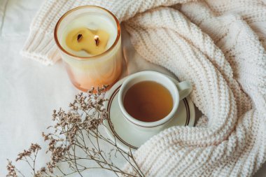 Ev dekoru. Örgü battaniye, mum, bir fincan sıcak çay, kurutulmuş çiçekler. Sıcak bir sonbahar. Düş.