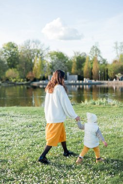 Genç, güzel, mutlu bir anne ve küçük oğlu parkta yürüyor. Sıcak bir sonbahar. Ilık bahar.