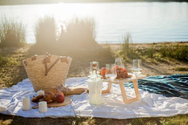 Gölün kenarında meyveler, hamur işleri ve şarapla güzel bir sonbahar pikniği. Güneş ışınları.