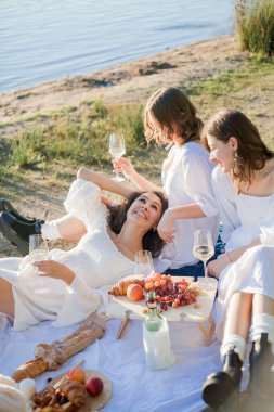 25 yaşında genç ve güzel bir kadın göl kenarında sonbahar pikniğinde. Bir bardak beyaz şarap, hamur işleri. Mutlu mankenler neşeyle sohbet ediyor..