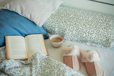 Bir kupa sıcak kahve, kitap, yatakta yumuşak terlikler. Yatakta kahvaltı. Rahat bir ev. Kış.