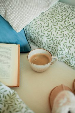 Bir kupa sıcak kahve, kitap, yatakta yumuşak terlikler. Yatakta kahvaltı. Rahat bir ev. Kış.