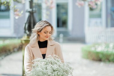 Çiçek buketiyle güzel genç bir sarışın. Avrupa 'da manolya çiçeği açmış genç bir kadının portresi. Bahar.