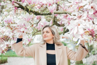 Çiçek buketiyle güzel genç bir sarışın. Avrupa 'da manolya çiçeği açmış genç bir kadının portresi. Bahar.