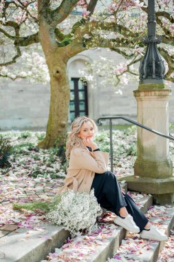 Çiçek buketiyle güzel genç bir sarışın. Avrupa 'da manolya çiçeği açmış genç bir kadının portresi. Bahar.