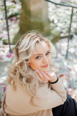 Çiçek buketiyle güzel genç bir sarışın. Avrupa 'da manolya çiçeği açmış genç bir kadının portresi. Bahar.