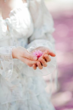Açık romantik elbiseli güzel sarışın. Avrupa 'da bir kentin çiçek açan sakura ağacının yanında genç bir kadının portresi. Bahar.