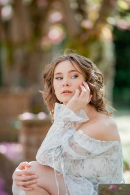 Açık romantik elbiseli güzel sarışın. Avrupa 'da bir kentin çiçek açan sakura ağacının yanında genç bir kadının portresi. Bahar.