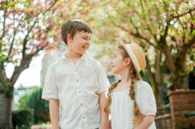 Kiraz çiçeği bahçesinde oynayan mutlu küçük çocuklar. Tatlı erkek ve kız kardeşler..